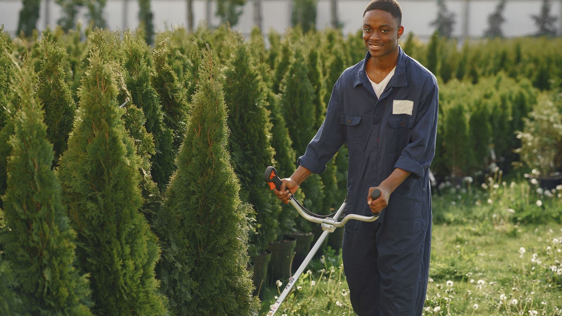 A landscaper loading a commercial mower onto a trailer at dawn, dewy lawn and truck in the background