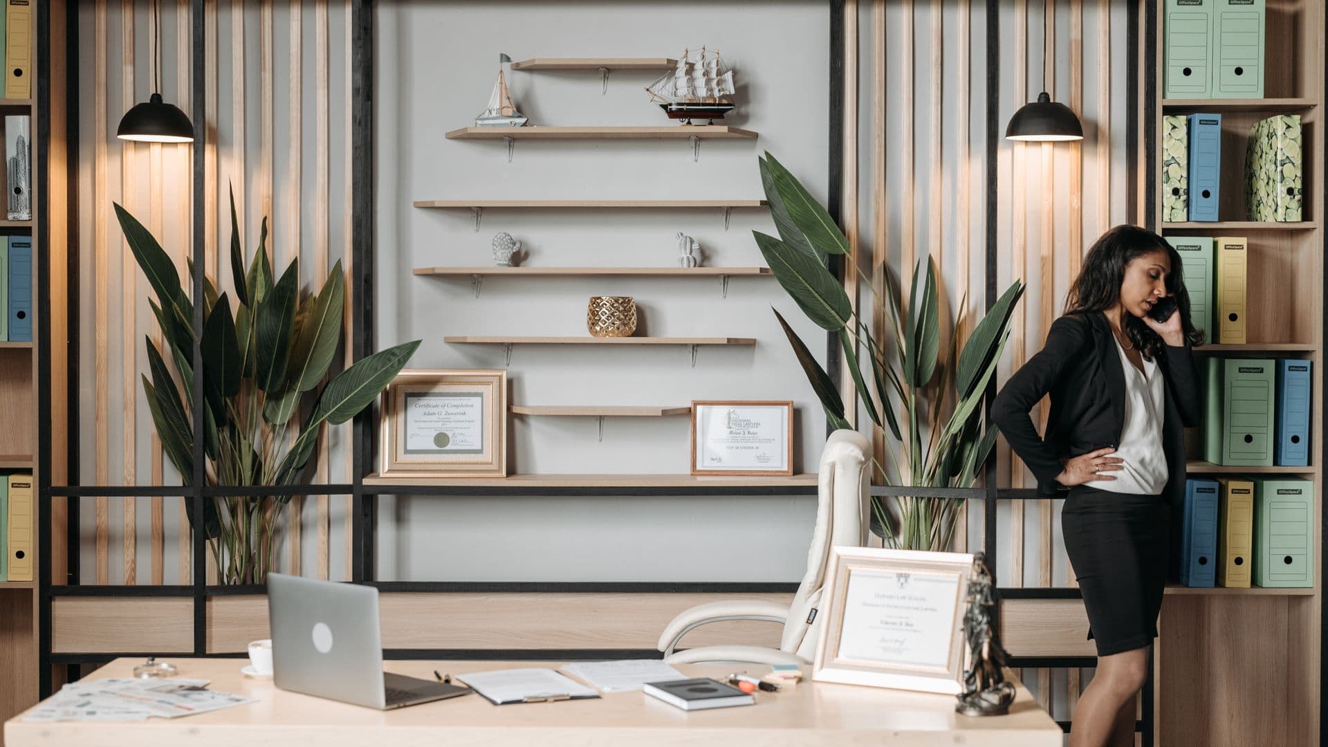 A lawyer at a desk reviewing documents with a phone and legal pad, warm office light, bookshelf behind